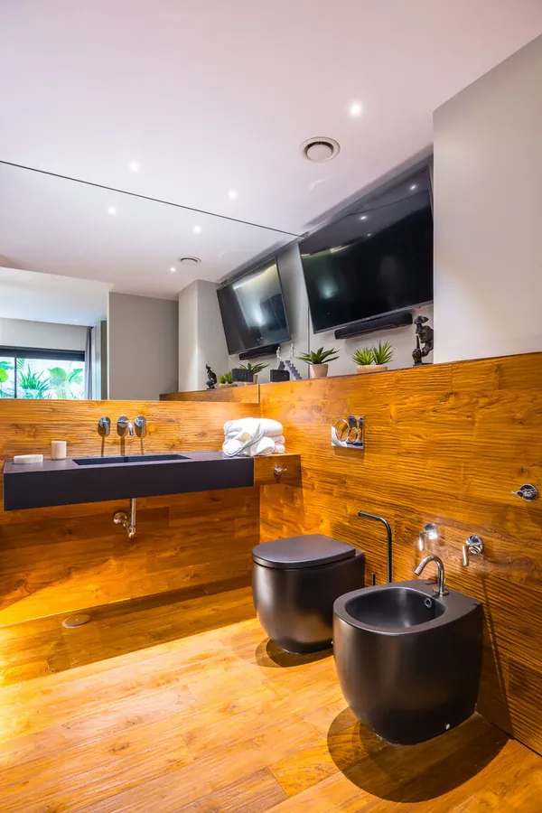 Bagno padronale Santopaolo 1 con lavabo sospeso in pietra, sanitari neri e parete in legno