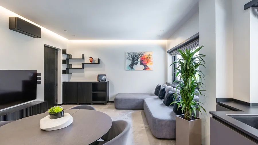 Zona living Santopaolo 2 con smart TV, libreria e divano modulare in tessuto grigio