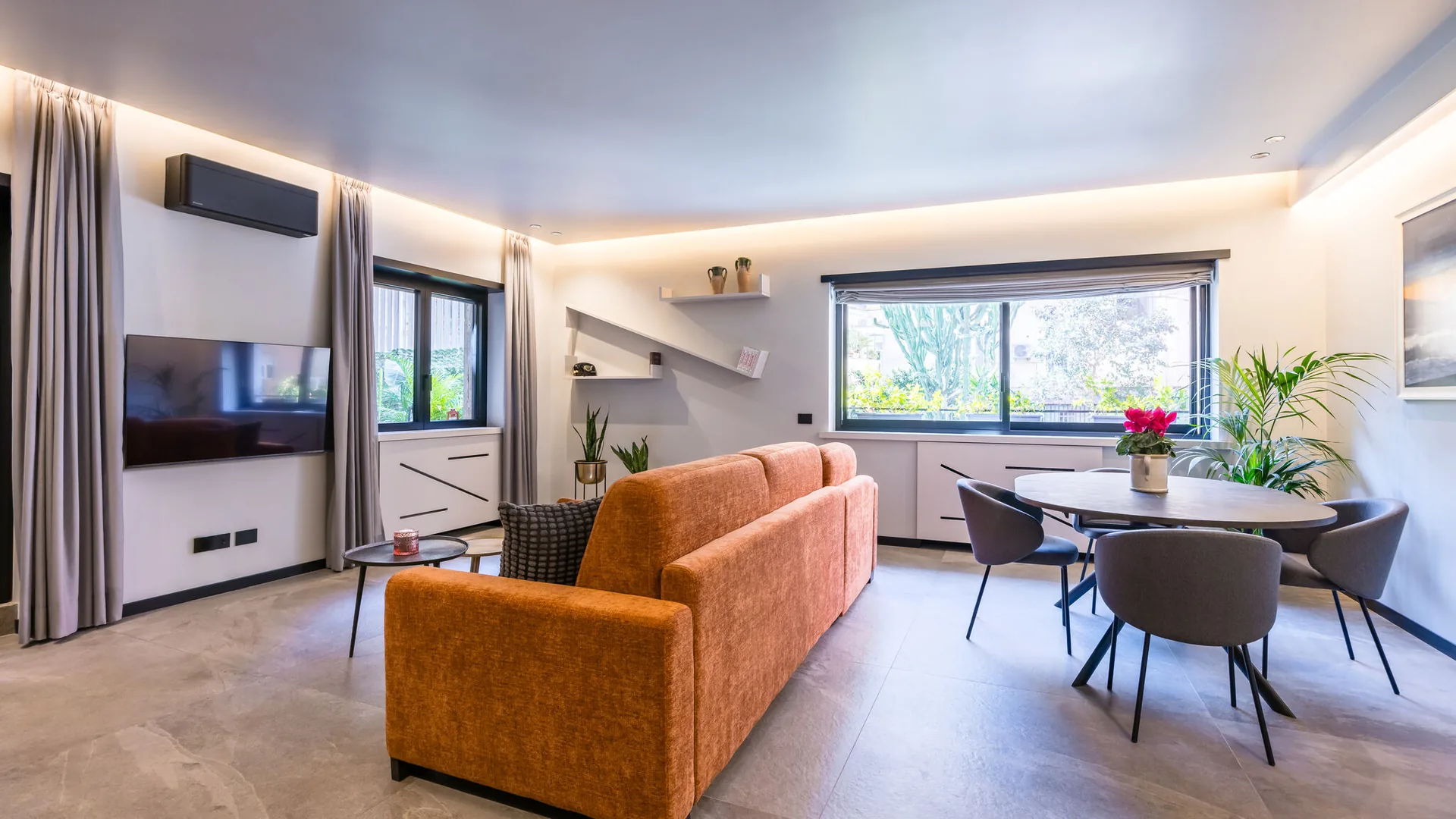 Living room in Santopaolo 3 with sofa bed, dining table and large windows onto greenery, 70 sqm apartment in Chiaia