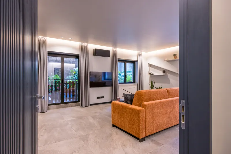 Ingresso sul salone di Santopaolo 3, divano arancione e porta finestra sul balcone
