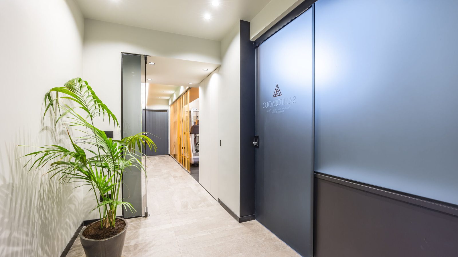 Corridoio interno piano wellness Santopaolo con pianta decorativa e logo su porta
